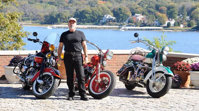 Billy Joel in front of three of his vintage motorycles