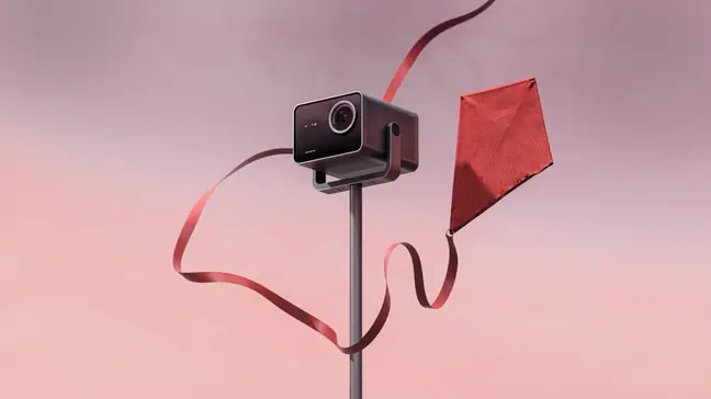 A pink-tinted sky serves as the backfrop for a cube-like projector with a kite.