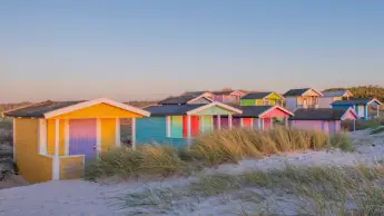 Colorful cabanas line the white-sand beaches of Skanör, Sweden.